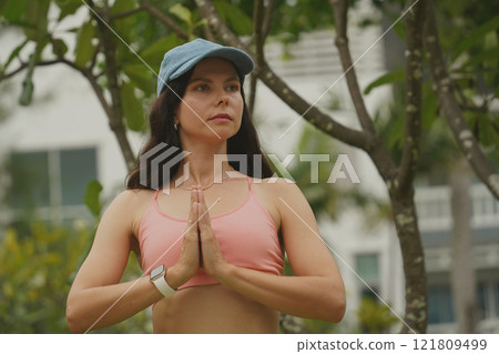 A young woman is joyfully practice a yoga mat in a beautiful park 121809499