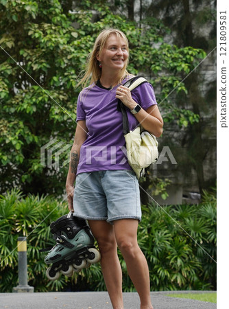 A woman is rollerblading gracefully on a road located in a park A woman is rollerblading gracefully on a road located in a park 121809581