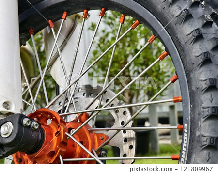 Closeup view of a motorcycle wheel on a grassy field 121809967