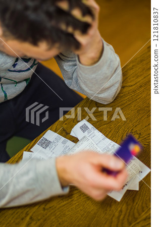 Stressed Man Reviewing Bills and Credit Card at Wooden Table. High quality photo 121810837