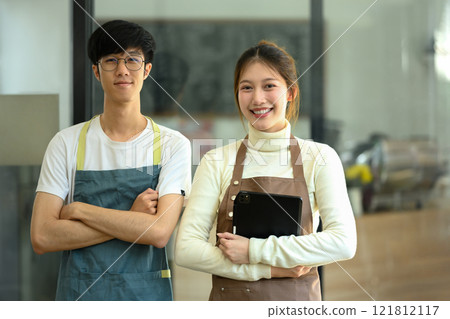 Small business entrepreneurs standing in their their coffee shop and smiling to the camera 121812117