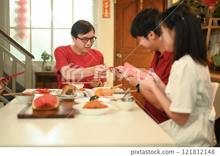 Senior man giving red envelop angpao during Chinese New Year celebrations symbolizing blessings and good fortune 121812148