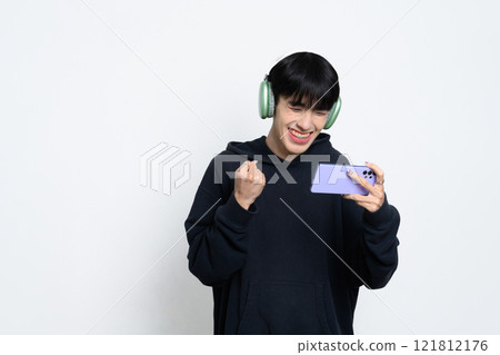 Happy man wearing headphones celebrating a gaming victory on smartphone 121812176