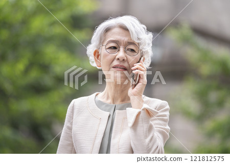 一位表情陰沉的老婦人在智慧型手機上說話 一位表情陰沉的老婦人在智慧型手機上說話 121812575