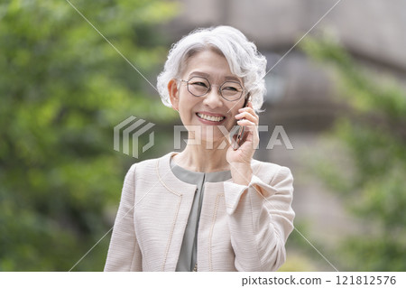 60 多歲的微笑女士用智慧型手機交談 60 多歲的微笑女士用智慧型手機交談 121812576