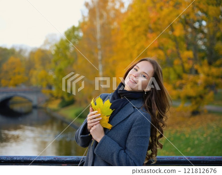 Girl, autumn image near yellow leaves in gray coat. Riga, Latvia 121812676