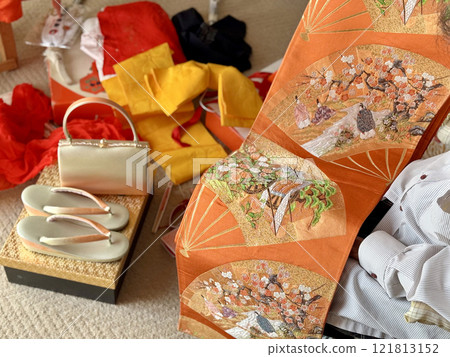 A woman looking at the accessories and obi of her kimono 121813152
