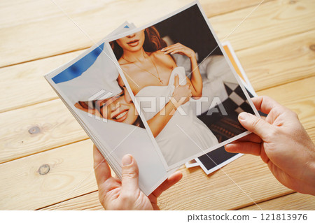 Men's hands put on the wooden table and show wedding photos. 121813976