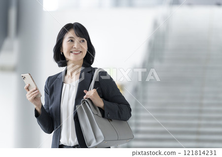 一位 50 歲出頭的女商人，擁有智慧型手機 121814231