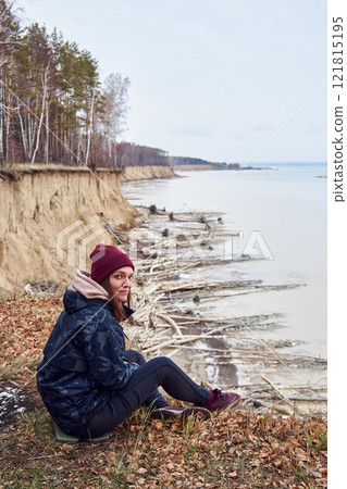 Young Woman sits on a cliff above the coast and admires nature, enjoy solitude Young Woman sits on a cliff above the coast and admires nature, enjoy solitude 121815195