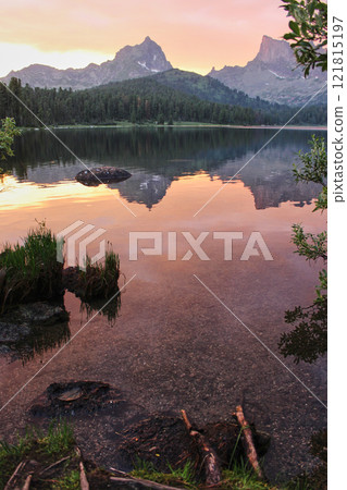 The mountains are reflected in the crystal clear water of the lake at sunset 121815197