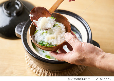 Serve rice porridge with seven herbs into bowls 121815669