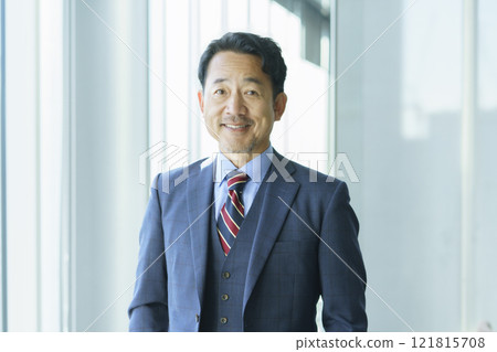 Portrait of a middle-aged man standing by a window in an office. Photo courtesy of Tokyo Electronics College, Denpa Gakuen Corporation. 121815708