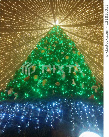 Colorful Christmas tree adorned with lights and ornaments during a festive evening celebration Colorful Christmas tree adorned with lights and ornaments during a festive evening celebration 121816013