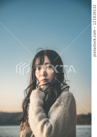 A woman gazing into the distance on the beach at sunset 121816132
