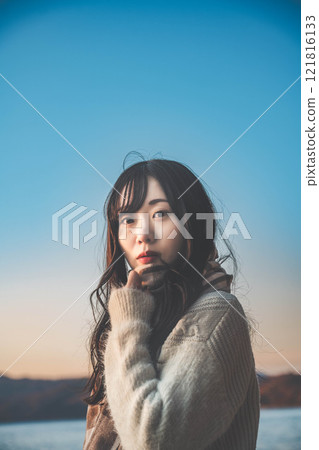 A woman gazing into the distance on the beach at sunset A woman gazing into the distance on the beach at sunset 121816133