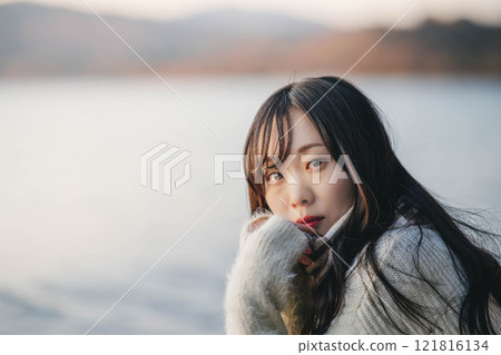 A woman gazing into the distance on the beach at sunset 121816134