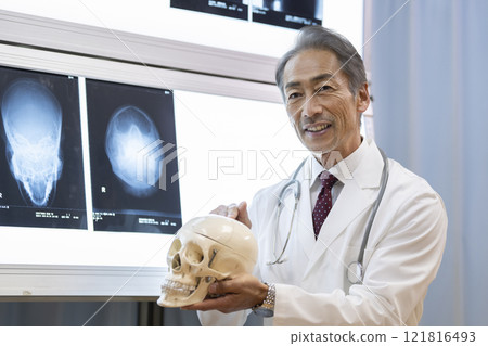 一位男醫生拿著頭骨模型並解釋 121816493