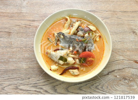 boiled bass fish head and mushroom in tom yum soup on plate 121817539