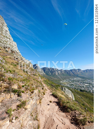 Paragliding from Lions Head with a beautiful view of Table Mountain in Cape Town, South Africa. Lush green trees growing in harmony on rocky terrain. Tourist attraction for adventurous explorers Paragliding from Lions Head with a beautiful view of Table Mountain in Cape Town, South Africa. Lush green trees growing in harmony on rocky terrain. Tourist attraction for adventurous explorers 121818964