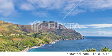 A landscape of a mountainside with an ocean view and blue sky background with a lush, green botanical garden or national park. A scenic environment with rocky and rough terrain in a remote location 121819216