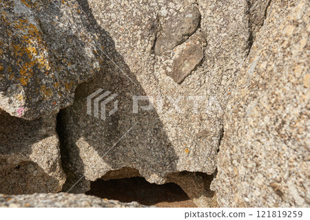 Small crevice or gully formed by the erosion of sea water. Large boulders or sandstones on beach shore or in the mountains.Texture detail of sedimentary rock acting as wave breaker on coastal seaside 121819259