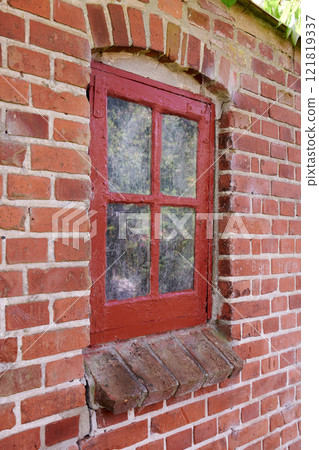 Old dirty window in a red brick house or home. Decaying casement with redwood frame on a historic building with clumpy paint texture. Exterior details of a windowsill in a traditional town or village Old dirty window in a red brick house or home. Decaying casement with redwood frame on a historic building with clumpy paint texture. Exterior details of a windowsill in a traditional town or village 121819337