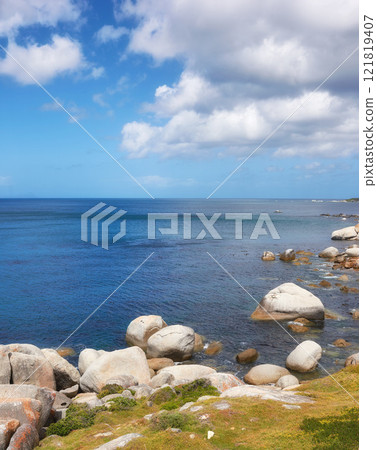 Scenic ocean view of beach with rocks or boulders and sea water washing onto shore during peaceful summer vacation in tropical resort and island overseas. Rough texture and detail of rocky coastline Scenic ocean view of beach with rocks or boulders and sea water washing onto shore during peaceful summer vacation in tropical resort and island overseas. Rough texture and detail of rocky coastline 121819407