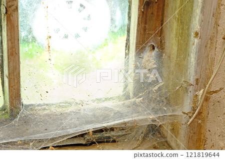Closeup of an old window with webs and dirt in an abandoned home. Zoom in on wooden frame, texture and design of a messy timber wood styled window with macro details of a dusty, dirty surface Closeup of an old window with webs and dirt in an abandoned home. Zoom in on wooden frame, texture and design of a messy timber wood styled window with macro details of a dusty, dirty surface 121819644