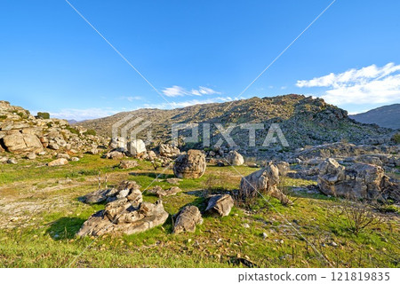 A rocky mountainside landscape with green lush grass growing in an ecological rural environment. Beautiful field on rough terrain in nature with a scenic blue sky in the Western Cape during summer A rocky mountainside landscape with green lush grass growing in an ecological rural environment. Beautiful field on rough terrain in nature with a scenic blue sky in the Western Cape during summer 121819835