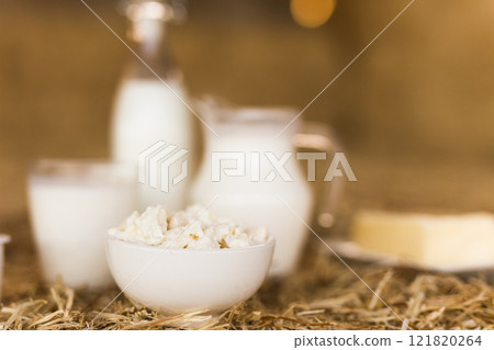 Milk, cottage cheese, cream, cheese on table against the background of hay 121820264
