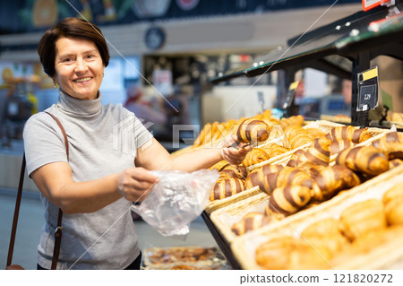 Moman walks through a supermarket to shop 121820272