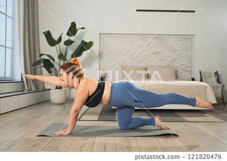 Yoga fitness workout training. Woman practicing yoga at home. Plus size female doing sports exercise on yoga mat indoor. Girl in sportswear have training workout for weight loss. Sport and fitness 121820476