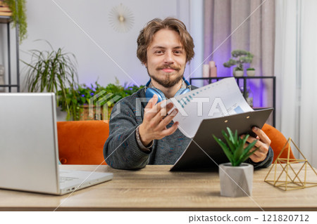Happy man freelancer work with documents from home, analyzing information prepare financial report 121820712