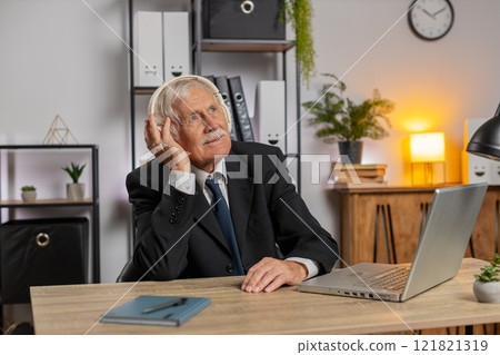 Overjoyed senior businessman sitting at home office desk listening to music through headphones Overjoyed senior businessman sitting at home office desk listening to music through headphones 121821319