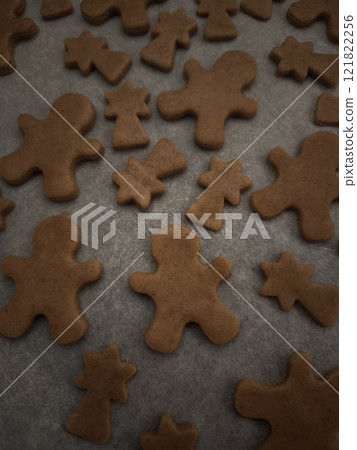 Gingerbread men and comets cookies baking on a tray and paper, ready for the holiday season christmas Gingerbread men and comets cookies baking on a tray and paper, ready for the holiday season christmas 121822256
