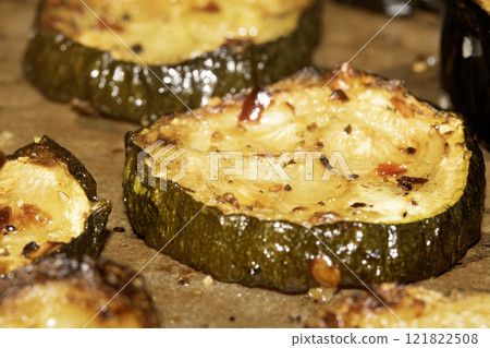 A roasted sliced seasoned aubergine eggplant courgette with salt and herbs cooked in the oven close up 121822508
