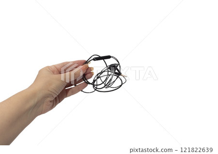 Female hand holding black wired headphones isolated on white background. Modern gadgets for communication Female hand holding black wired headphones isolated on white background. Modern gadgets for communication 121822639