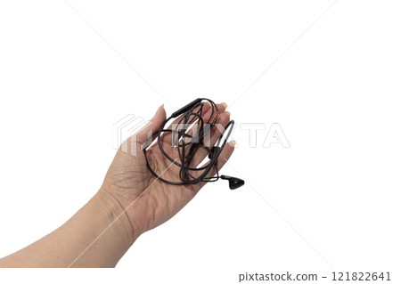 Female hand holding black wired headphones isolated on white background. Modern gadgets for communication 121822641