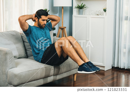 Athletic body and active sporty man using furniture for gaiety home exercise. 121823331