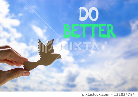 Do better symbol. Concept words Do better on beautiful blue sky. Beautiful blue sky clouds background. Hand holds wooden bird. Business and do better concept. Copy space. 121824784