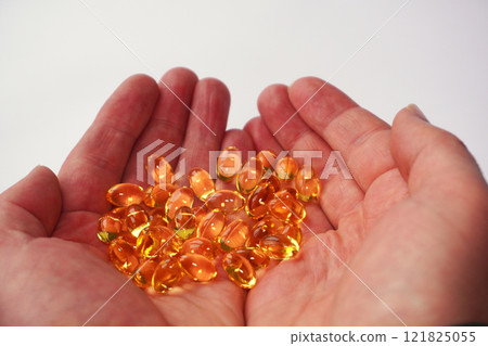 Close-up of hands holding golden fish oil capsules, symbolizing health benefits, omega-3 nutrients, and dietary supplementation. Close-up of hands holding golden fish oil capsules, symbolizing health benefits, omega-3 nutrients, and dietary supplementation. 121825055
