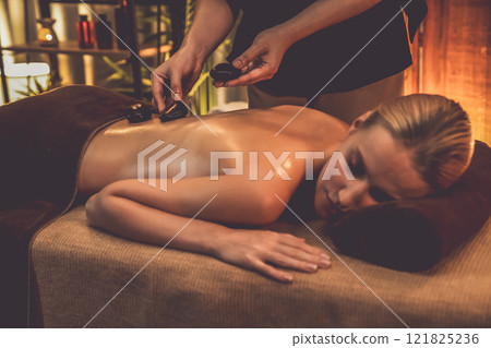 Hot stone massage at spa salon in luxury resort with warm candle light.Quiescent Hot stone massage at spa salon in luxury resort with warm candle light.Quiescent 121825236