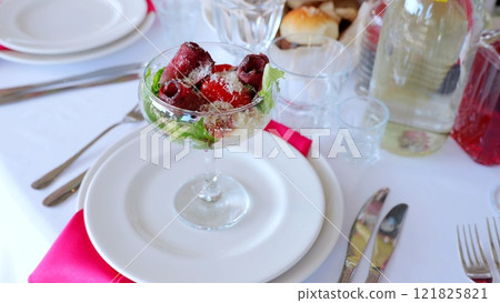 Grilled beef roulade stuffed with melted cheese, colorful vegetable filling, resting on white ceramic plate with soft pink linen napkin nearby 121825821