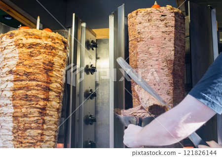 Unrecognizable person cooking turkish kebap or kebab on a rotating grill Unrecognizable person cooking turkish kebap or kebab on a rotating grill 121826144