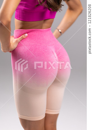 Confident woman in stylish pink fitness shorts, close-up view of vibrant workout wear, colorful activewear concept 121826208