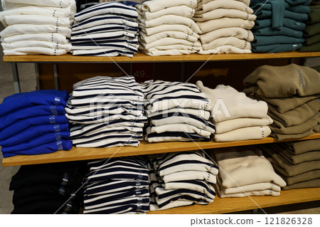 Cozy sweaters neatly arranged on wooden shelves in a retail store atmosphere Cozy sweaters neatly arranged on wooden shelves in a retail store atmosphere 121826328