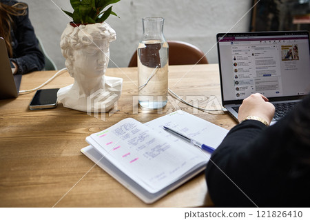 Workspace with Decorative Bust Planter, Open Notebook, Laptop, Water Pitcher, Creative Office Setting Concept Workspace with Decorative Bust Planter, Open Notebook, Laptop, Water Pitcher, Creative Office Setting Concept 121826410