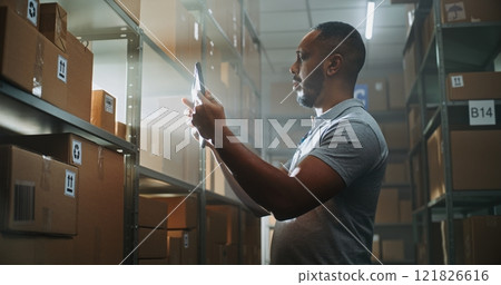 African American Warehouse Associate Scans Parcel Using Tablet Computer, Checks Information 121826616