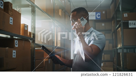 African American Logistics Manager Talks with Client on Phone, Uses Tablet Computer 121826631